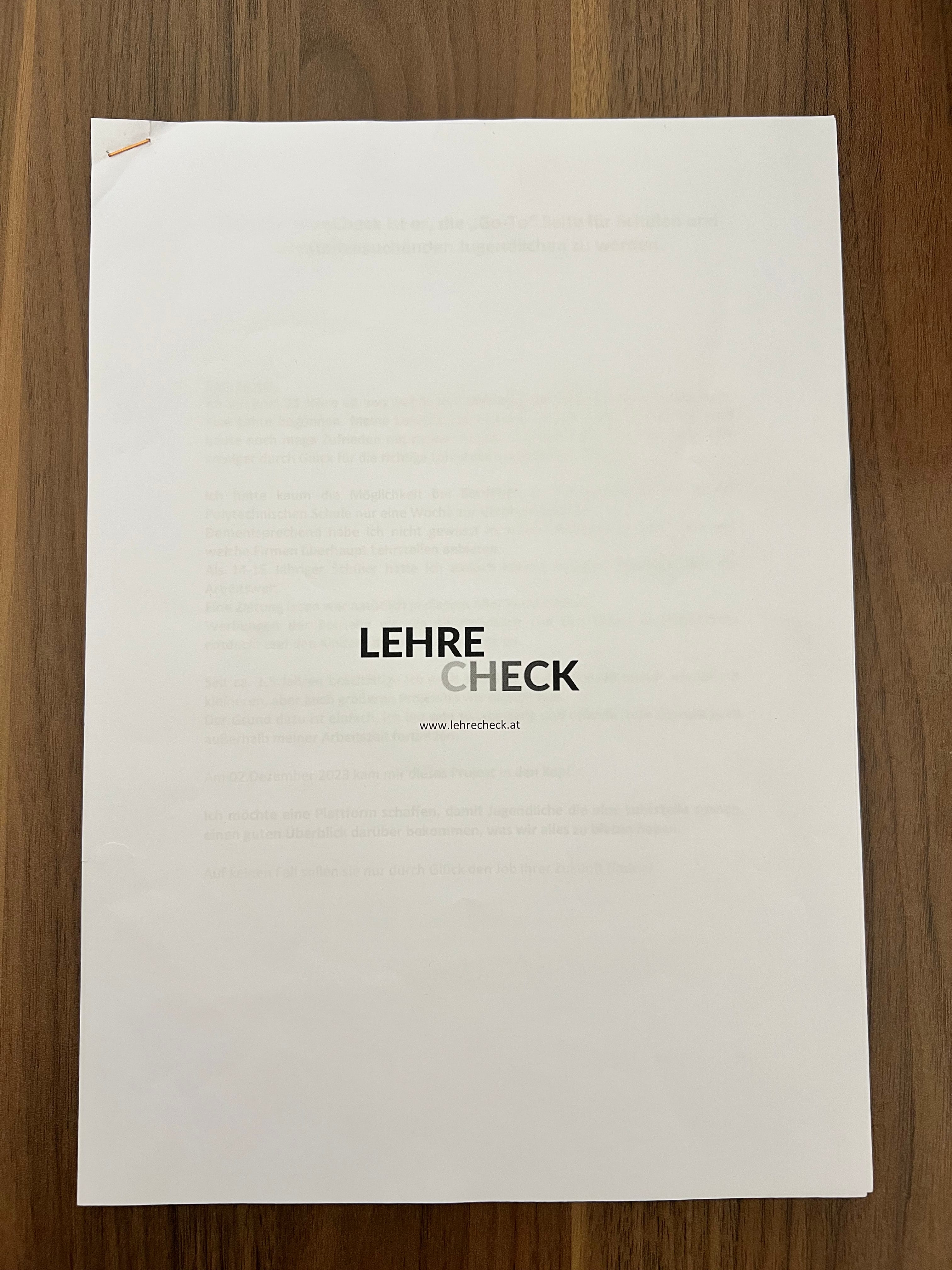 Weißes Papier auf einem Holztisch mit dem Logo „LEHRE CHECK“ und der Website-Adresse www.lehrecheck.at.